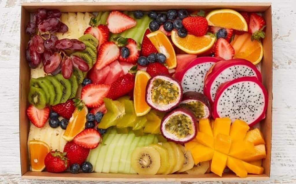 Fresh tropical and mixed fruit platter with strawberries, blueberries, kiwi, dragon fruit, mango, and citrus slices.