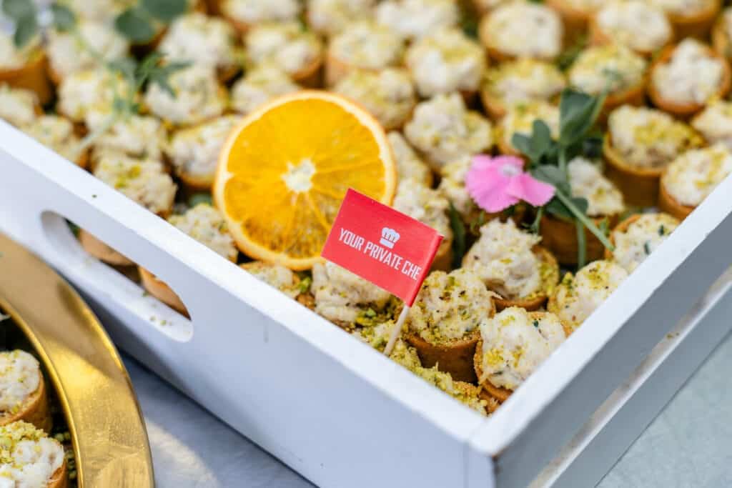 Freshly prepared canapés with orange slices and edible flowers for private events by Your Private Ch.